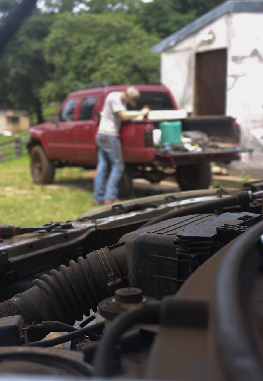 Capó de camioneta con mecánico trabajando en el fondo